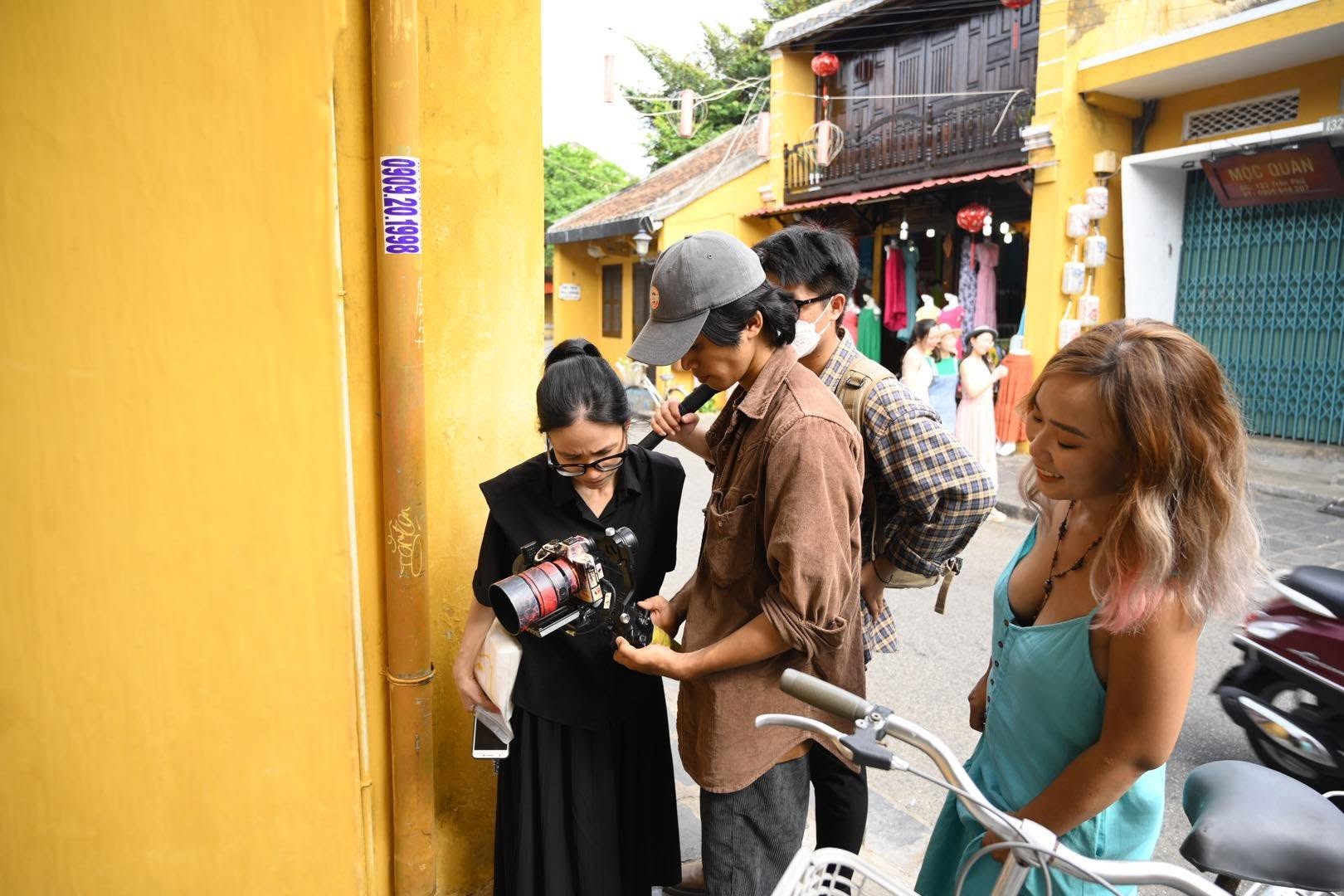 The Lele Linen team reviewing camera footage with a customer during a photoshoot on a Hội An street.